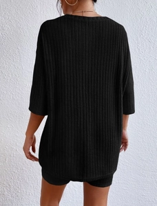 Detail of black knit two-piece set featuring breathable ribbed texture on t-shirt and shorts