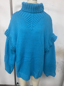 Détail du pull en maille bleu vif avec manches à volants et texture de tricot en relief