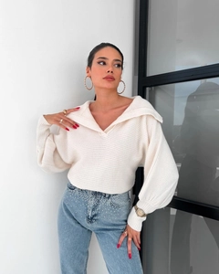 Details des weißen Rippstrickpullovers mit V-Ausschnitt und eleganten Laternenärmeln