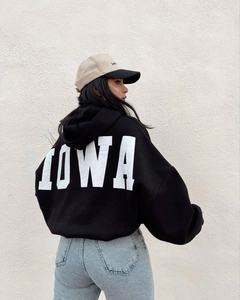 Detalle de sudadera negra oversize con capucha, estampado IOWA blanco y hombros caídos