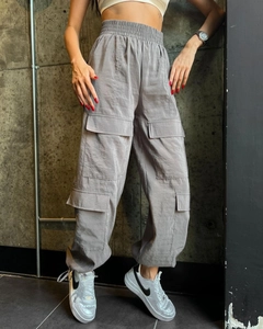Detail of high-waisted light gray cargo pants featuring large utility side pockets