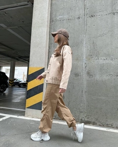 Close-up of beige stand collar jacket styled with cargo pants and a baseball cap