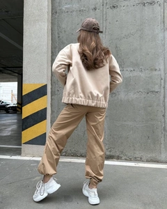 Back view of a casual beige stand-collar jacket and khaki joggers set for women