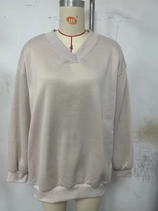 Detail of the oversized V-neck ribbed neckline and cuff on a beige sweatshirt