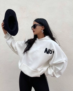 Primer plano de sudadera blanca oversize con estampado NO1 negro y bolsillo de canguro