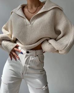 Detail eines beigen Strickpullovers mit Überkragen, Laternenärmeln und Kontrastnähten