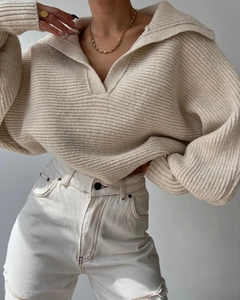 Detaillierte Strickstruktur des cremeweißen Oversize-Pullovers mit tiefem V-Ausschnitt