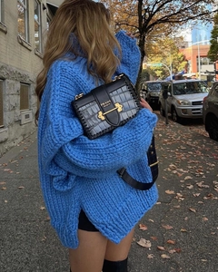 Détail d'un pull à col roulé bleu roi en maille épaisse avec torsades et manches larges