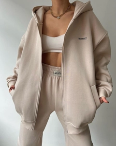 Detail of oatmeal hooded tracksuit with MAI STUDIOS CO. logo and ribbed crop top texture