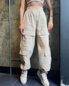 Detailed view of beige cargo pants with elastic high waist and large utility side pockets