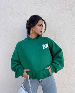 Detalle de sudadera verde oversize con hombros caídos y estampado de letras blancas