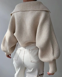 Detailaufnahme des beigen Strickpullovers mit großem Kragen und weißer Jeans mit Rissen