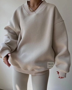 Close-up of oatmeal-colored baggy sweatshirt with high-quality stitched brand label detail