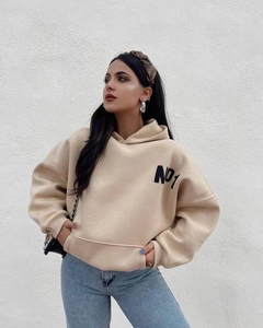 Detalle de sudadera oversize de felpa color albaricoque con estampado NO1 y hombros caídos