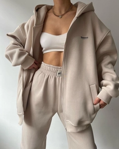 Detail view of beige hoodie and joggers featuring MCL STUDIOS CO. printed graphics