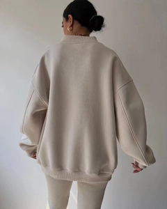 Detailed back view of a loose-fit beige sweatshirt with ribbed cuffs and hem details