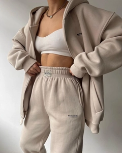 Detailed macro view of beige cotton tracksuit set showing MAI STUDIOS CO logo and fabric texture