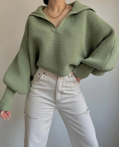 Detail eines salbeigrünen Strickpullovers mit Rippstruktur und modischem V-Ausschnitt Kragen