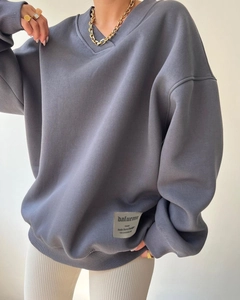 Detail of the high-quality dark grey fabric and woven label on a loose V-neck sweatshirt