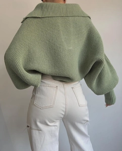 Detailansicht von salbeigrünem Strickpullover mit Kragen und weißer Jeans mit Rissen