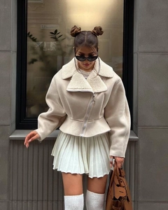 Detail of beige faux shearling cropped jacket featuring wide lapels and silver diagonal zipper