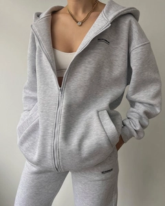 Detail of grey hooded tracksuit featuring zip-up fleece hoodie and matching joggers with logo