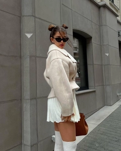 Detailed texture of women's cream faux shearling jacket with stylish lapel and waist belt