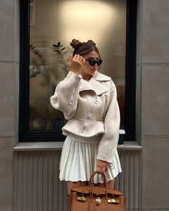 Detail of off-white faux fur lapel jacket and matching pleated skirt with accessories