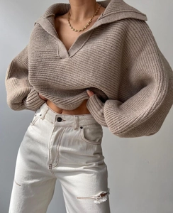 Detailansicht eines grob gestrickten Pullovers in Haferfarbe mit Revers und Laternenärmeln