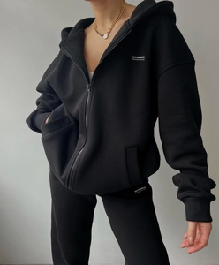 Close-up of black fleece tracksuit with MAI STUDIOS CO white lettering on the chest