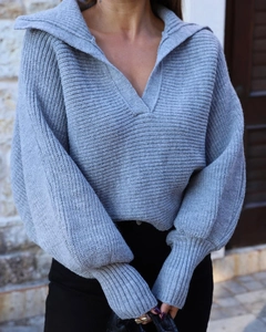 Detail eines hellgrauen Rippstrickpullovers mit großem Revers und weiten Laternenärmeln