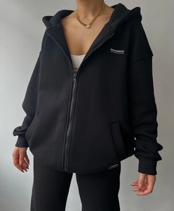 Detail of black zip-up hoodie featuring white MAI STUDIOS CO. text and soft fleece fabric