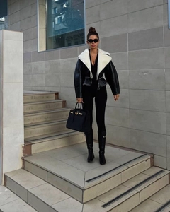 Detail of contrast white shearling collar on black faux leather jacket with zipper closure