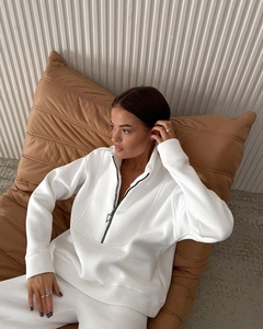 Detail of the white half-zip sweatshirt fabric and black metal triangle zipper puller