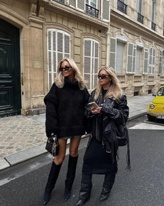 Photo street style d'une femme en pull noir oversize à col montant et bottes en cuir chic