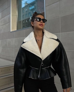 Close-up of women's biker jacket featuring white faux fur collar and black glossy faux leather