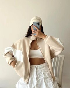 Detail of loose beige stand-collar jacket with white contrast sleeves and zipper front