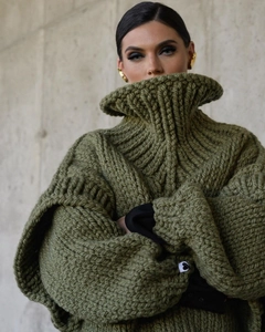 Détail du pull en maille épaisse vert olive avec texture côtelée et patch cœur au poignet