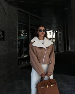 Detail view of stylish tan cropped jacket featuring warm white faux fur collar