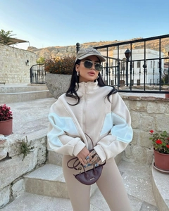 Detail of color-block patchwork sleeves and high-neck zipper on casual beige sweater