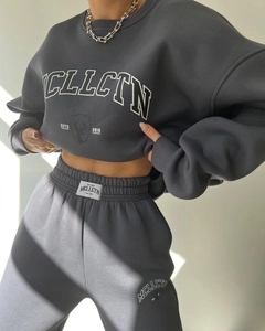 Detail of dark grey fleece tracksuit showing white MCLLCTN letter print and thick fabric