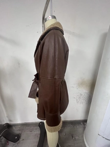 Detailed view of women's brown shearling jacket with beige faux fur trim and belt