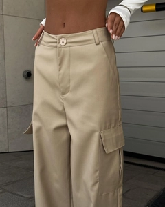 Detail of high waisted cargo pants showing large side pockets and khaki twill fabric texture