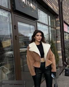 Detail of a brown suede jacket featuring white faux fur lining and a round zipper pull