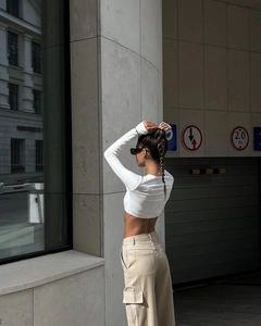 Detail of high-waist khaki cargo pants with functional side pockets and premium fabric