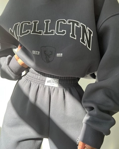 Detailed macro view of dark grey heavy fleece tracksuit featuring white printed logo and branding