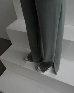 Detail view of grey-blue wide-leg trousers with side slit design on the leg opening