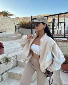 Detail view of women's casual jacket with metal zipper and stand collar in beige tones