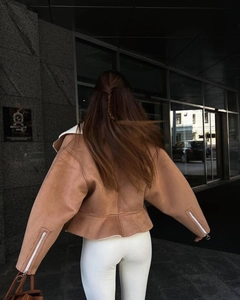 Back view of a cropped brown suede jacket with white faux shearling trim and sleeve zippers