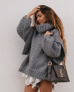 Détail d'un pull gris à col roulé en maille épaisse avec des motifs de torsades complexes
